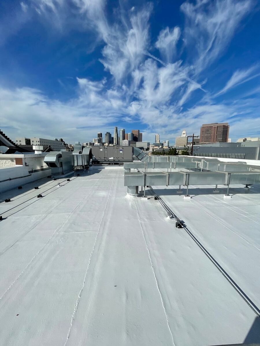 Finished white-coated flat roof with new ductwork at Nishi Hongwanji, the downtown Los Angeles skyline under a streaked blue sky